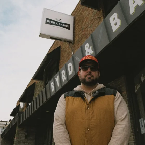 Man standing outside Byrd & Barrel brick building