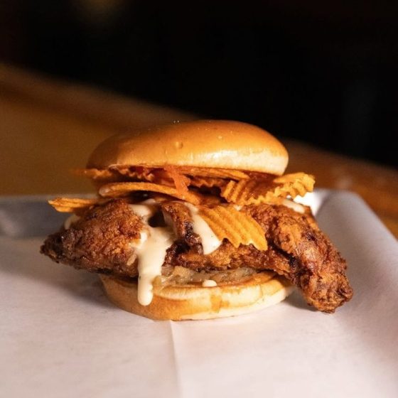 mother clucker fried chicken sandwich with sauce and red hot riplet potaton chips on a bun